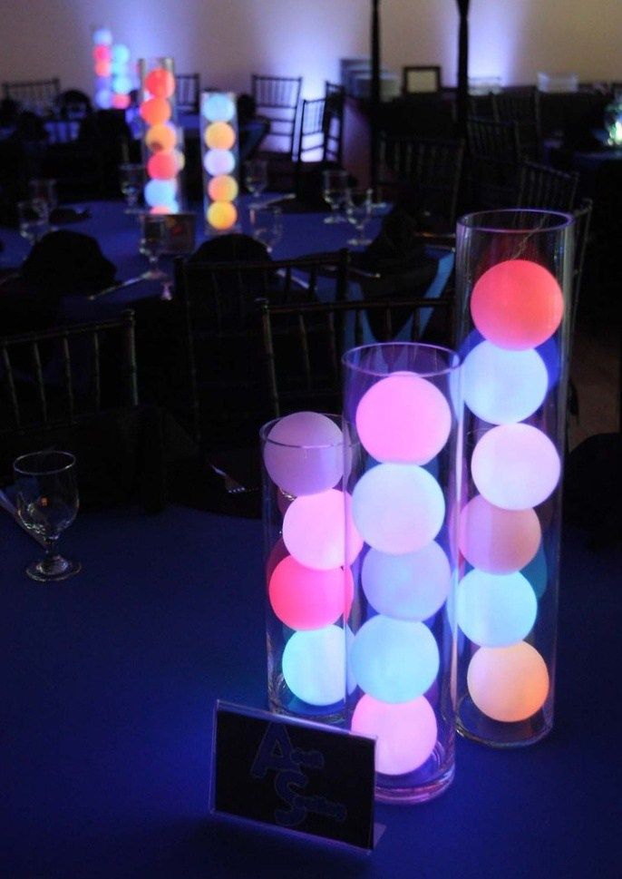 two tall vases filled with glowing balls sit on top of a blue table cloth