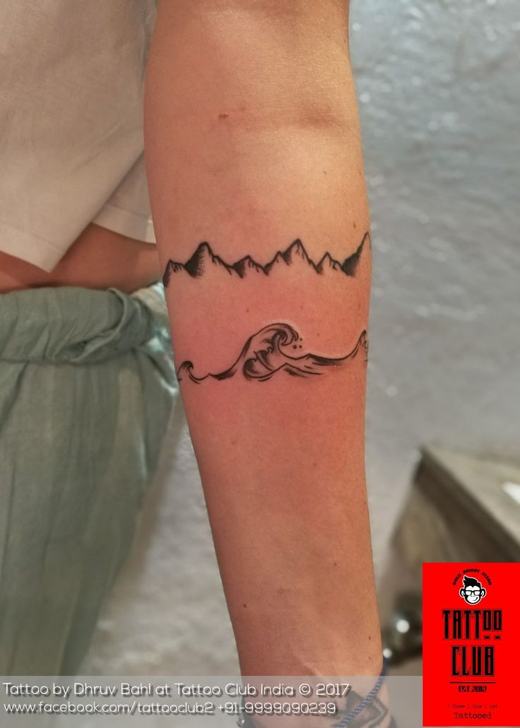 a woman's arm with a tattoo on it that has mountains and waves coming out of the water