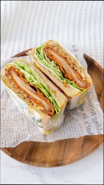 the sandwich is cut in half and sitting on top of a wooden plate with paper