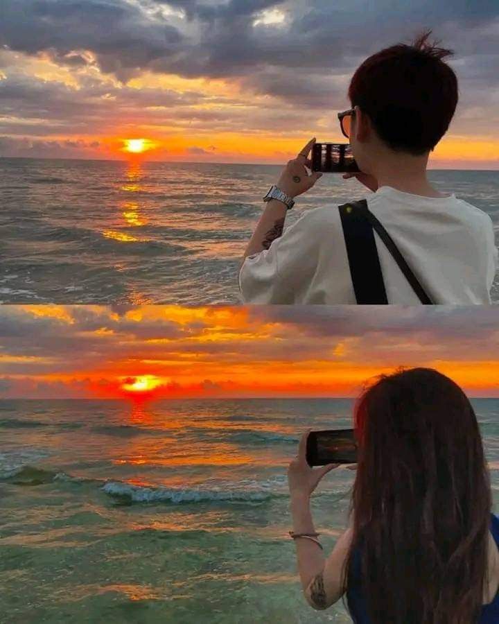 a woman taking a photo with her cell phone at the beach while the sun sets