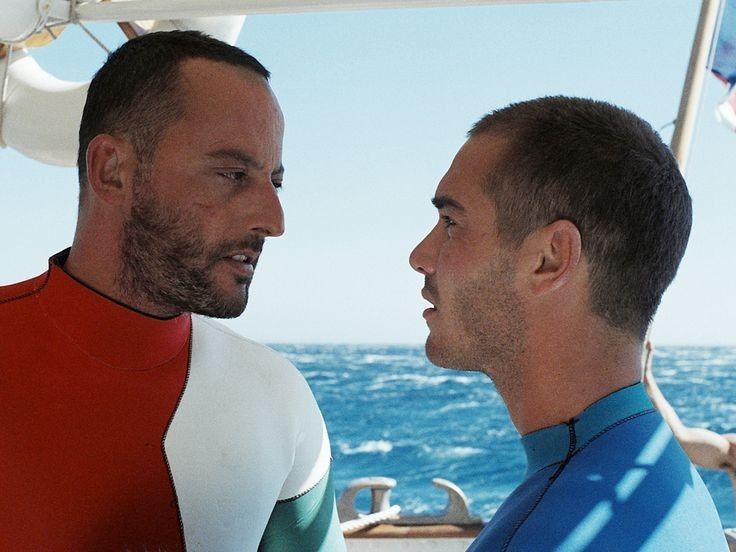 two men standing next to each other on a boat