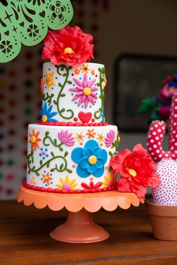 a multi - tiered cake decorated with flowers and polka dots sits on a table