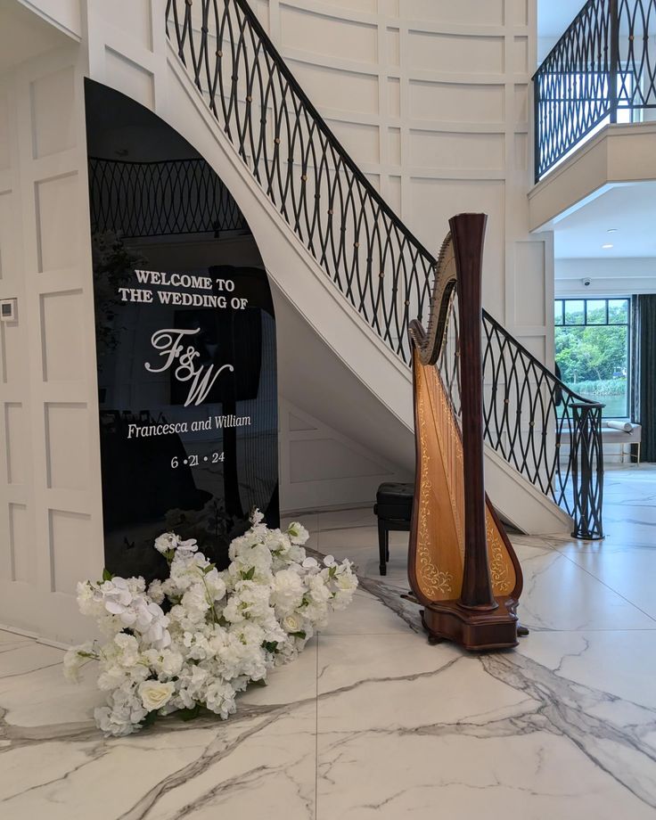 a harp sitting on the floor in front of a staircase with flowers next to it