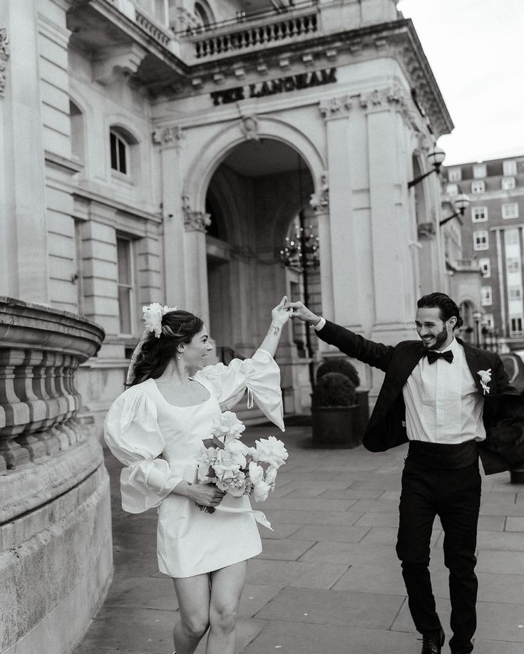 a man and woman are walking down the street holding hands in front of an old building