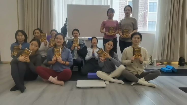 a group of women sitting on the floor holding up books