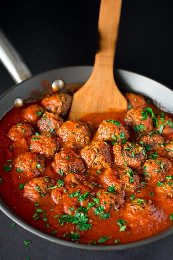 meatballs and sauce in a pan with a wooden spoon