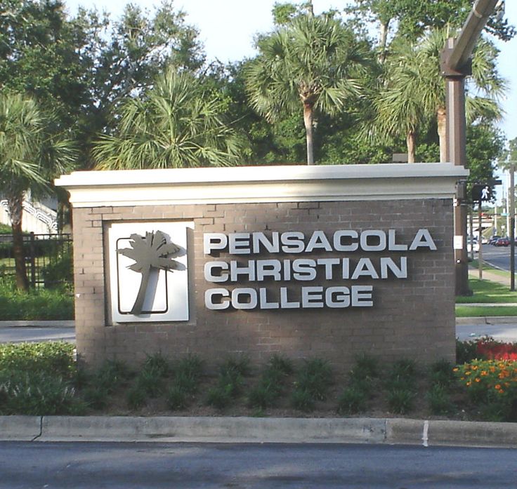 the sign for pensacola christian college is shown in front of some trees and bushes