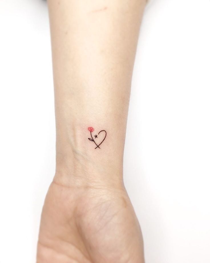 a small tattoo on the wrist of a woman's hand with a heart and flower