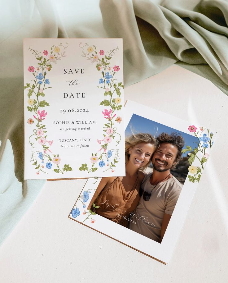 an image of wedding save the date cards on a table with flowers and leaves around them