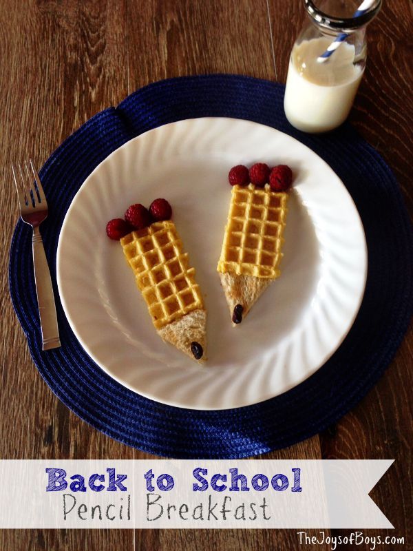 two waffles with raspberries are on a plate next to a glass of milk