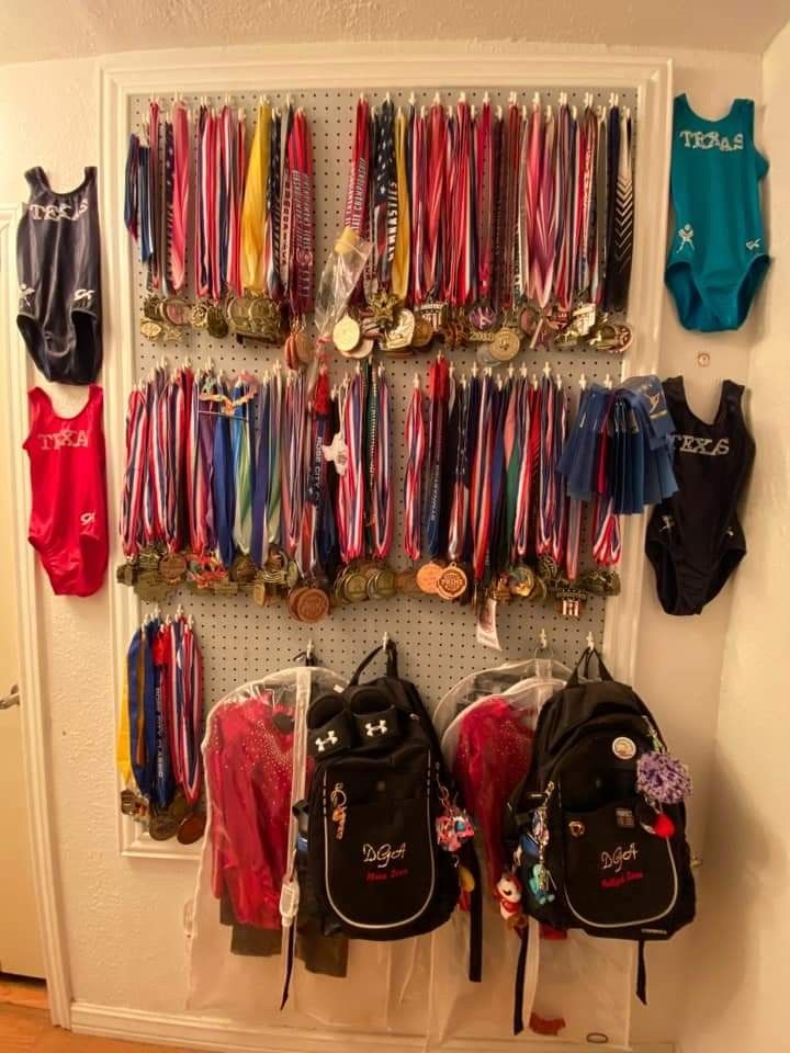 there are many medals and backpacks hanging on the wall next to eachother