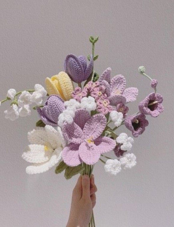 a hand holding a crocheted bouquet of flowers