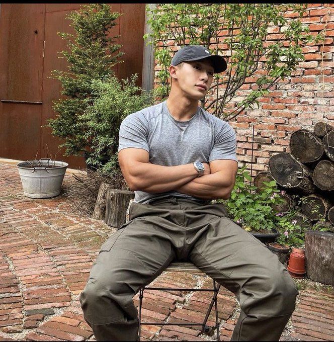 a man sitting on top of a chair in front of a brick building with his arms crossed