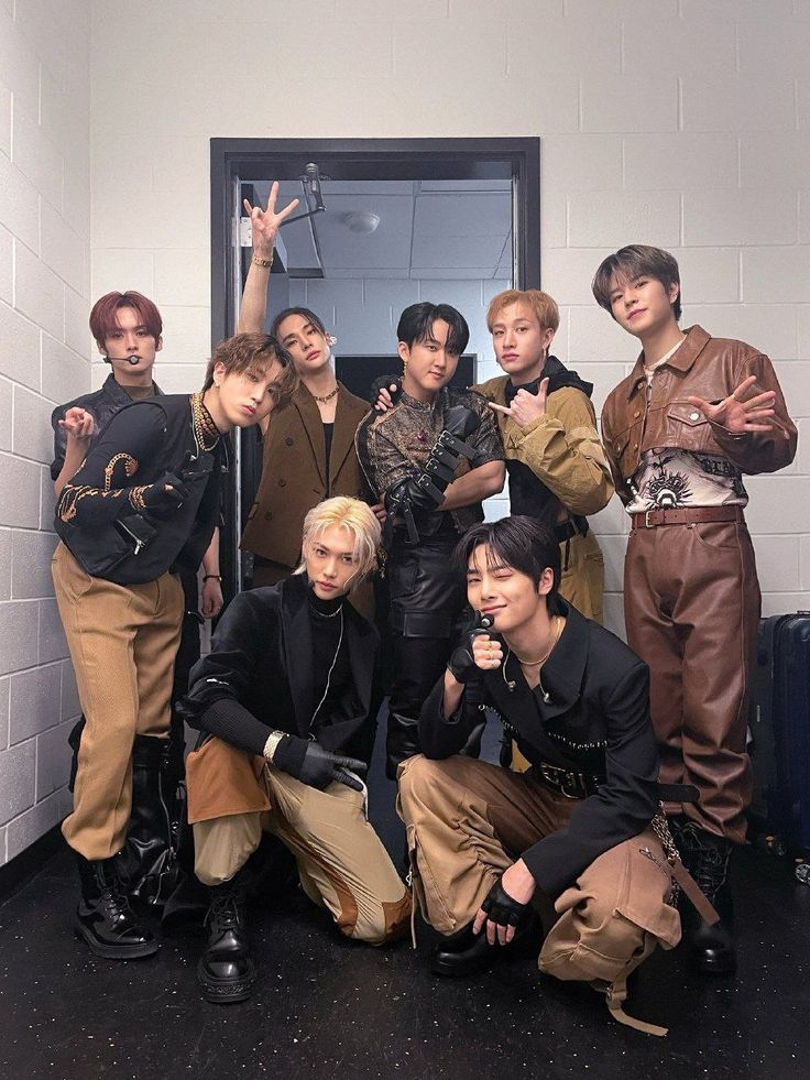 a group of young men standing next to each other in front of a door with their hands up