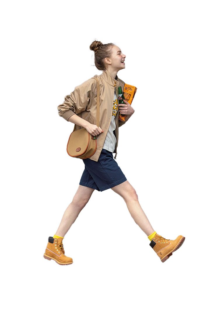 a woman walking with a book in her hand and a bag on her back while wearing yellow shoes