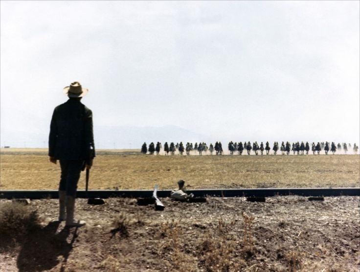 a group of people standing on top of a dry grass field