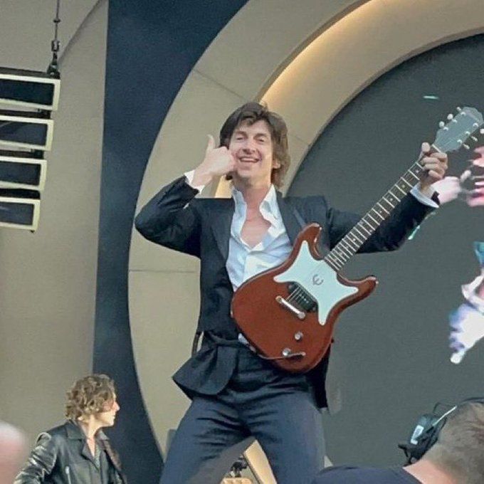 a man in a suit holding a guitar and talking on a cell phone while standing next to other people