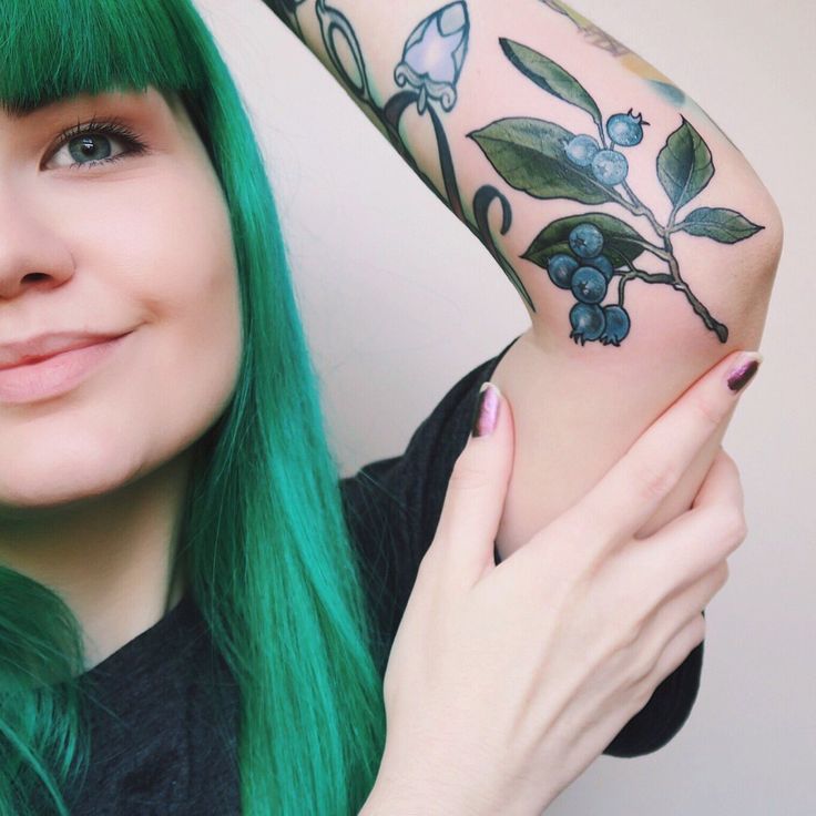 a woman with green hair and tattoos on her arm