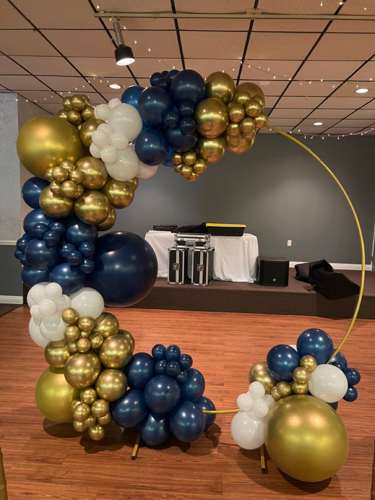 the balloon arch is decorated with gold, blue and white balloons