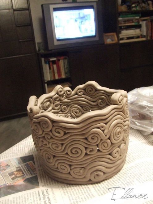 a ceramic bowl sitting on top of a table next to a tv set and bookshelf