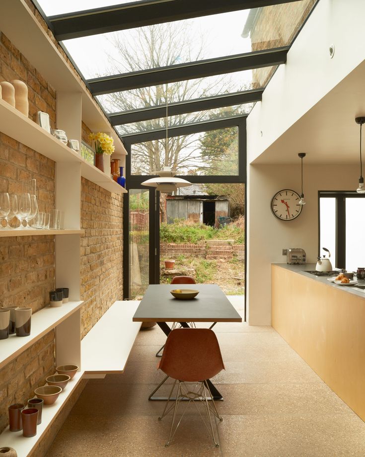 a dining room table and chairs in front of a brick wall with open shelves on it