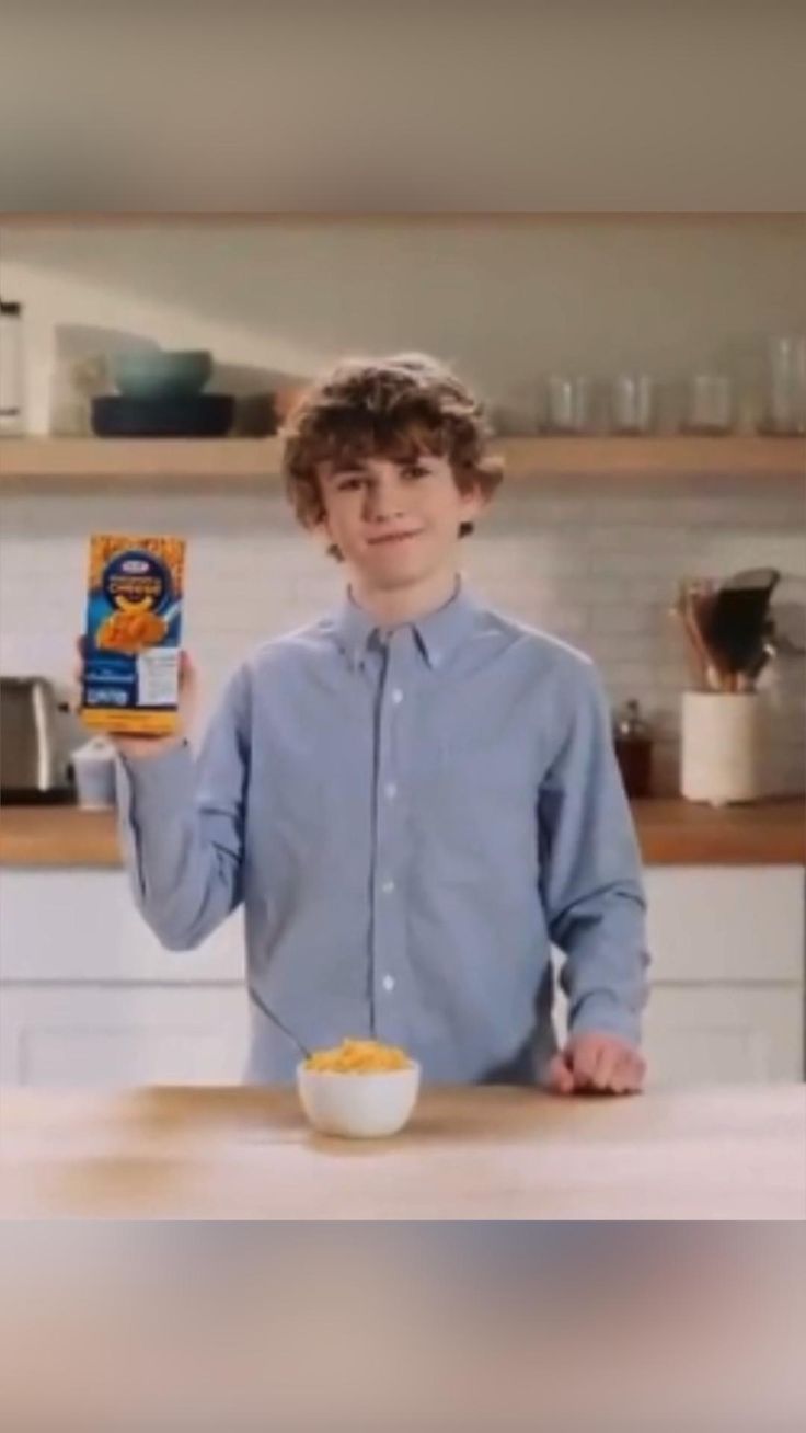 a young man holding up a box of cereal