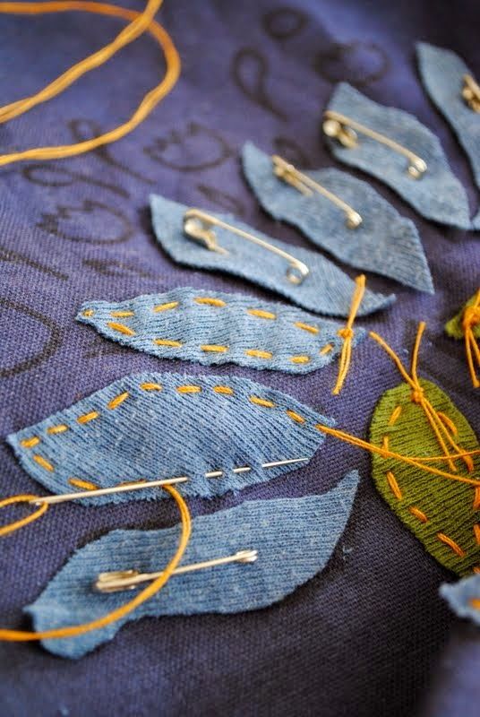 several pieces of blue fabric with yellow thread on them and some orange pins in the middle