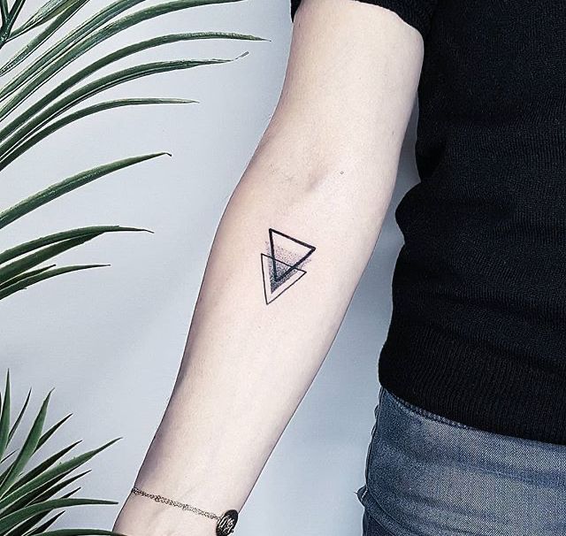 a woman's arm with a small triangle tattoo on the left inner forearm and wrist