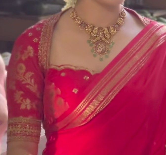 a woman wearing a red and gold sari with an elaborate necklace on her neck