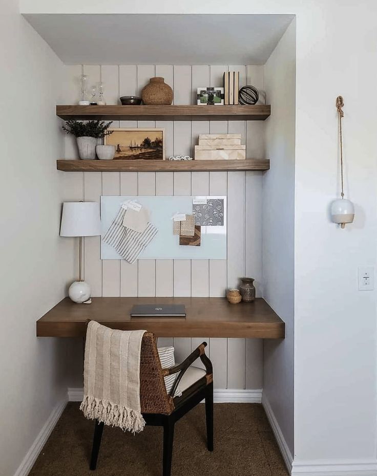 a wooden desk sitting in the corner of a room next to a wall mounted shelf