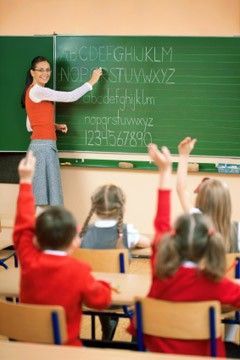 a teacher teaching children in front of a blackboard