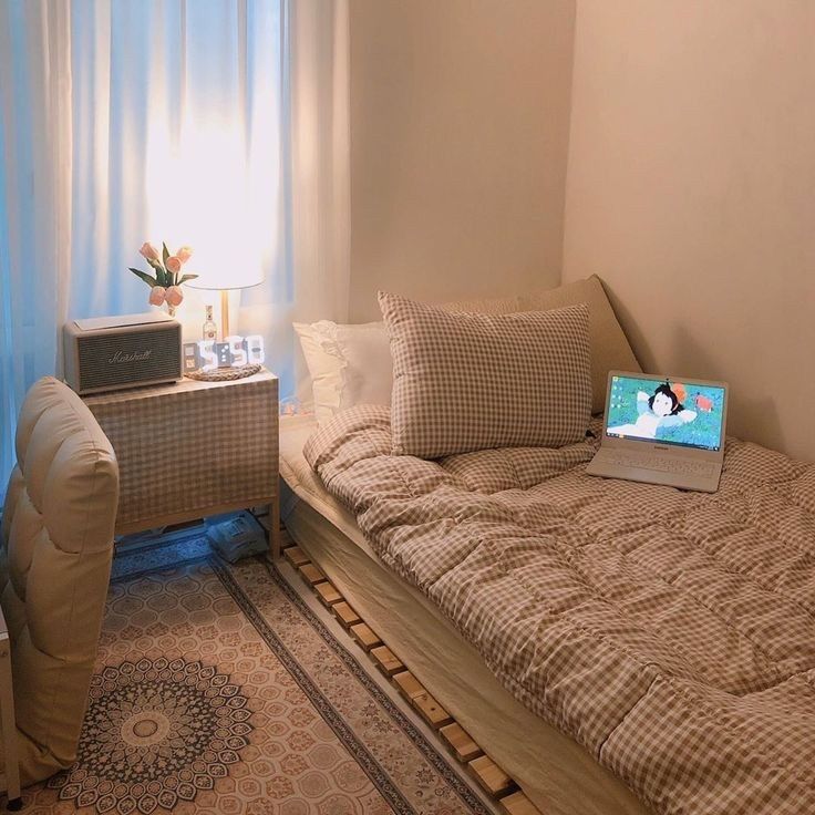 a laptop computer sitting on top of a bed next to a chair and window sill