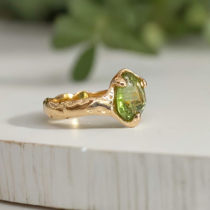 a yellow gold ring with an oval cut green peridoate stone in the center