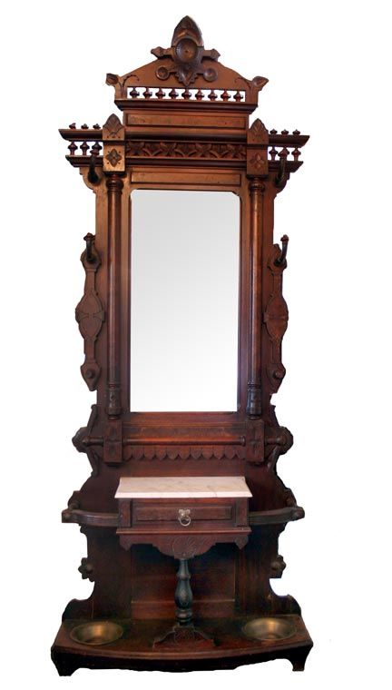 an ornate wooden mirror with a bench underneath it on display in front of a white background