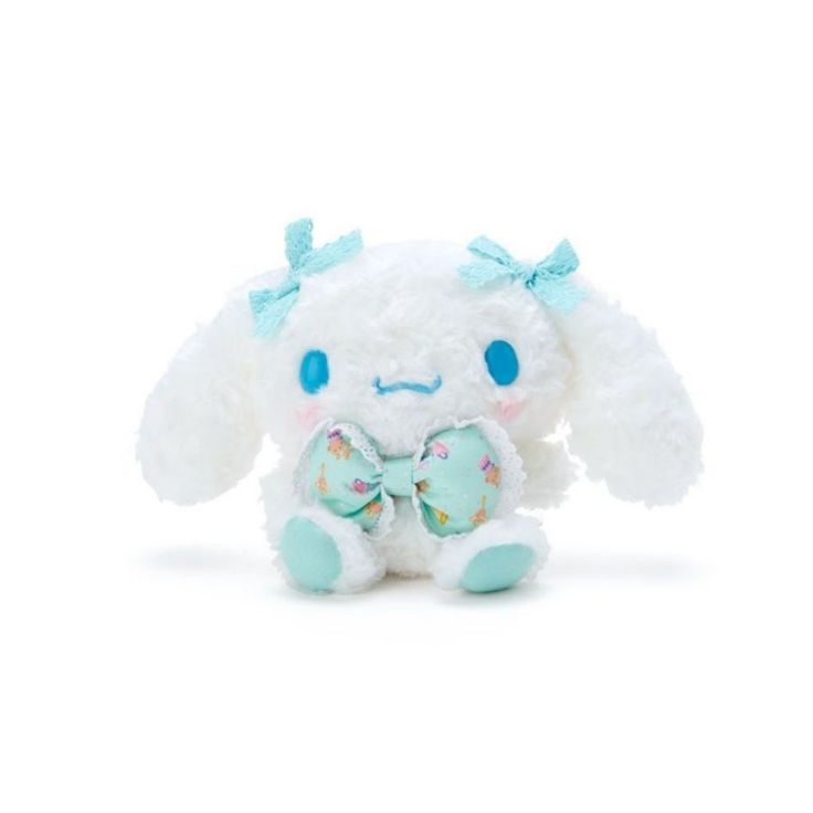 a white stuffed animal with blue eyes and a bow on it's head, sitting in front of a white background