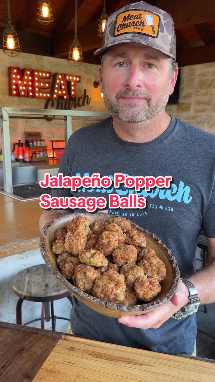 a man holding a bowl full of food in front of a restaurant sign that reads jalapeno poppai sausage balls