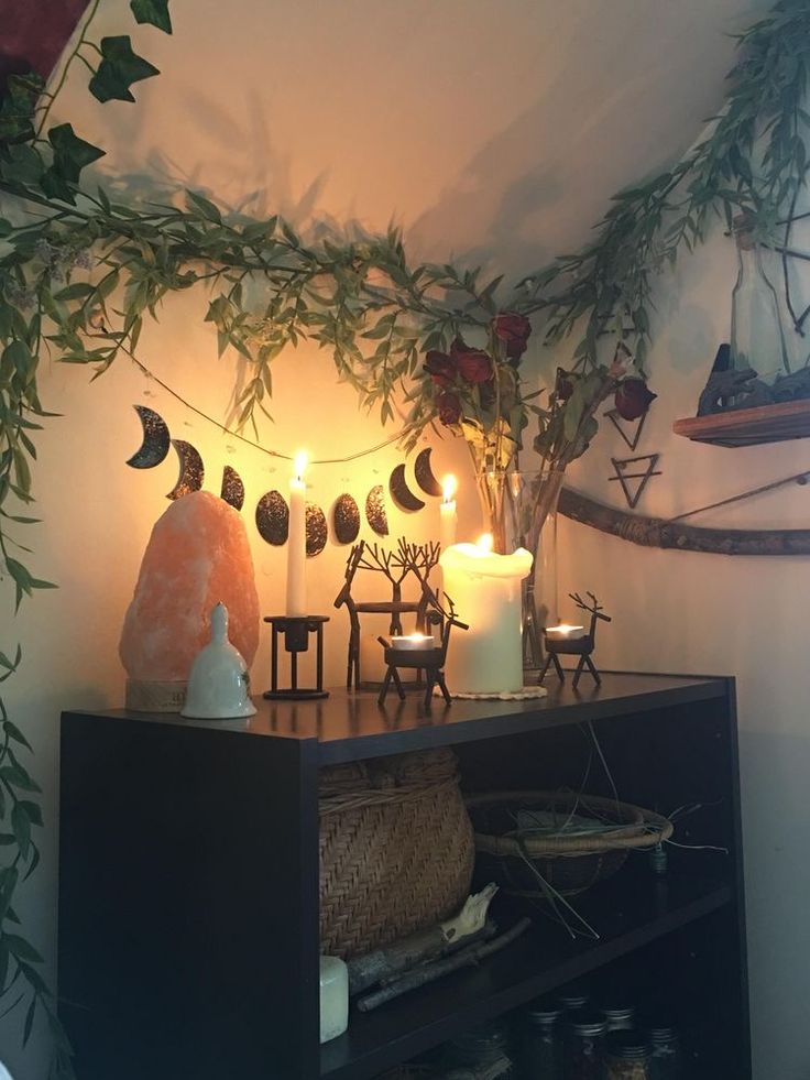 a shelf with candles and decorations on top of it in front of a wall hanging from the ceiling