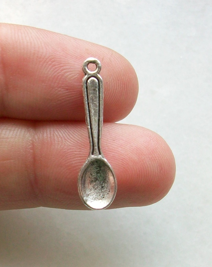 a tiny silver spoon shaped charm on someone's finger with the tip pointing up