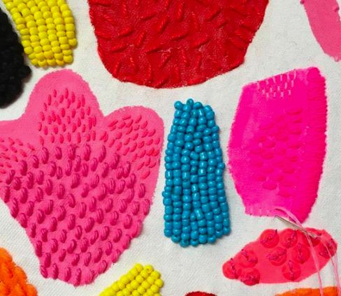 several different types of hair brushes and combs on a white cloth with colorful beads