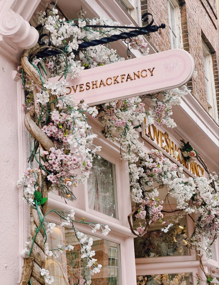 a pink store front with white flowers on the outside and sign that says veeshackfaacy