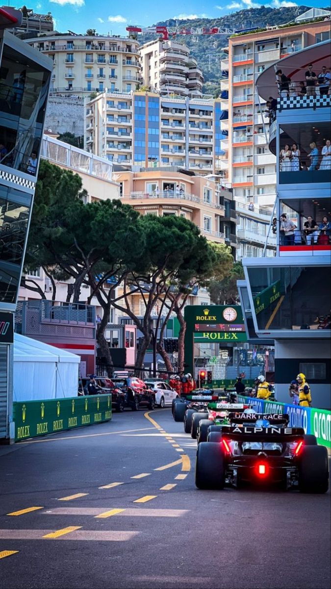 a race car driving down the street in front of tall buildings with people on it