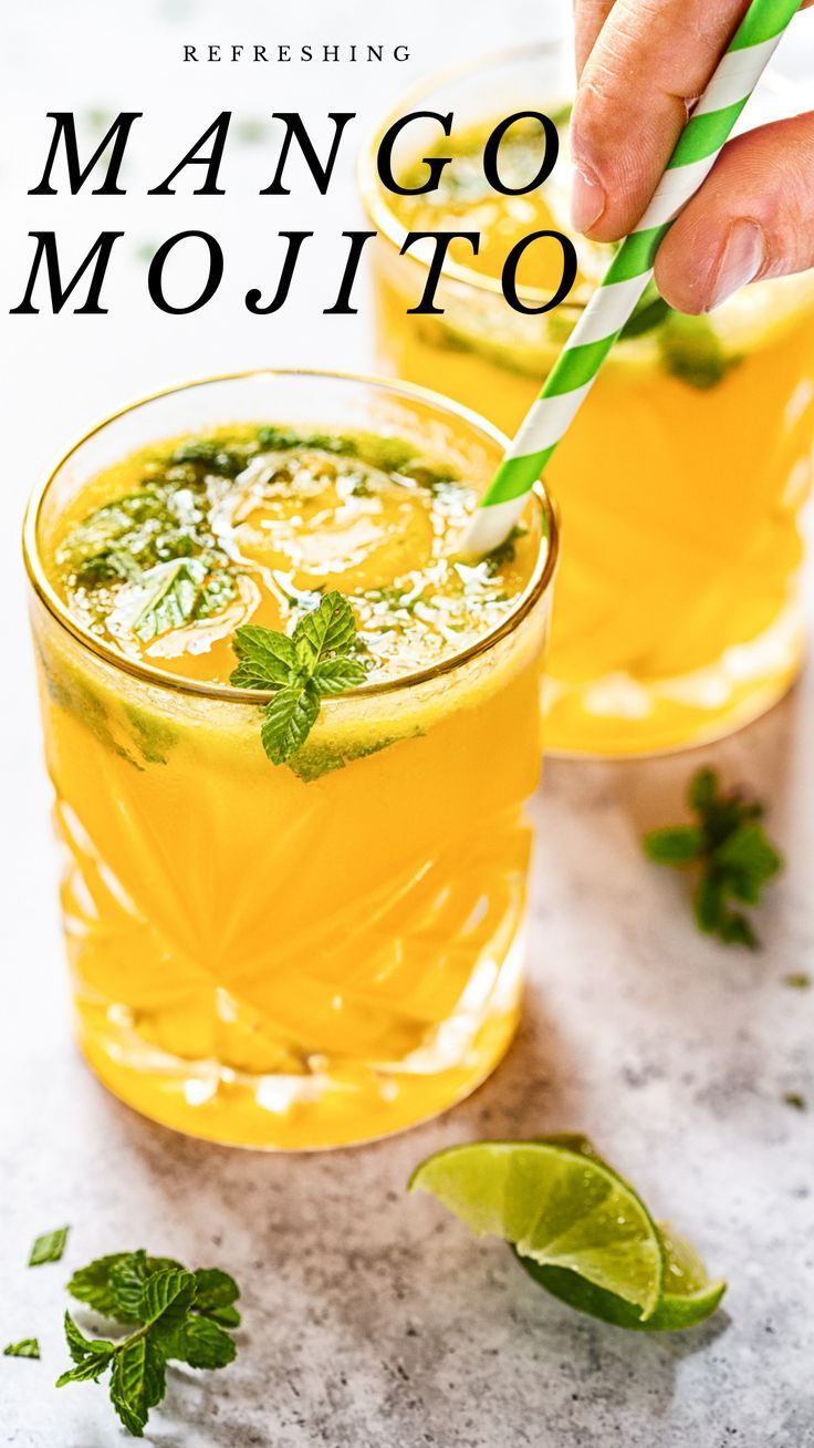 a person holding a green straw in front of two glasses filled with mango mojito