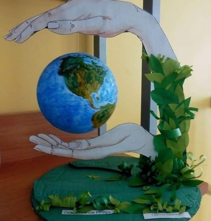 two hands reaching for the earth on top of a green base with plants growing out of it