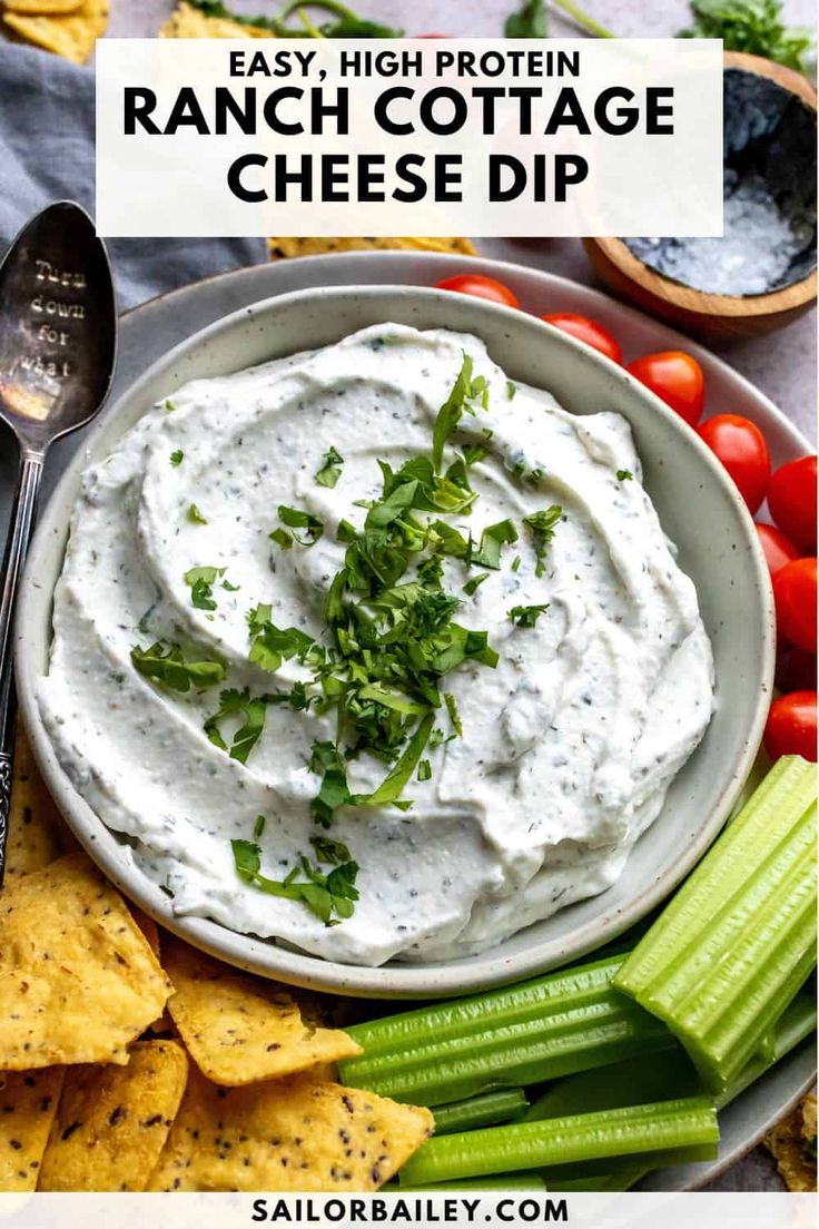 a white bowl filled with ranch cottage cheese dip surrounded by celery and tomatoes