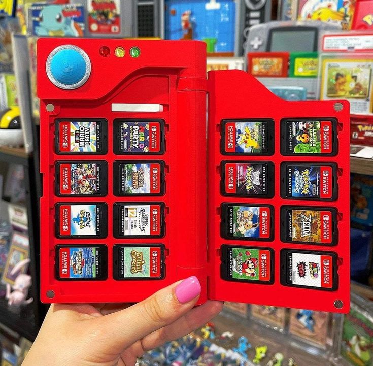 a person holding up a red nintendo game case in front of a store filled with video games