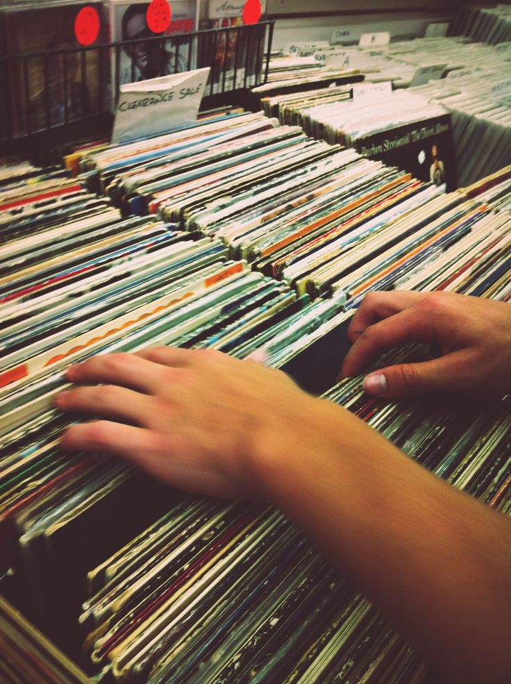 a person's hand is on top of a large amount of records in a record store