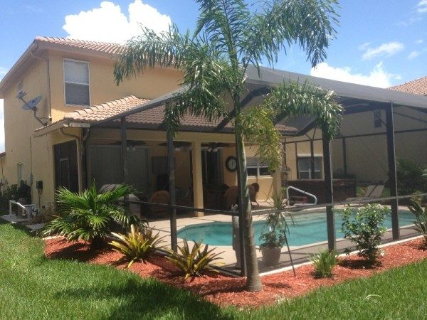 a house with a pool in the front yard and palm trees on the side of it