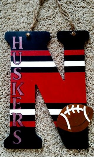 the letter n is made out of wood and has a football on it, hanging from a rope