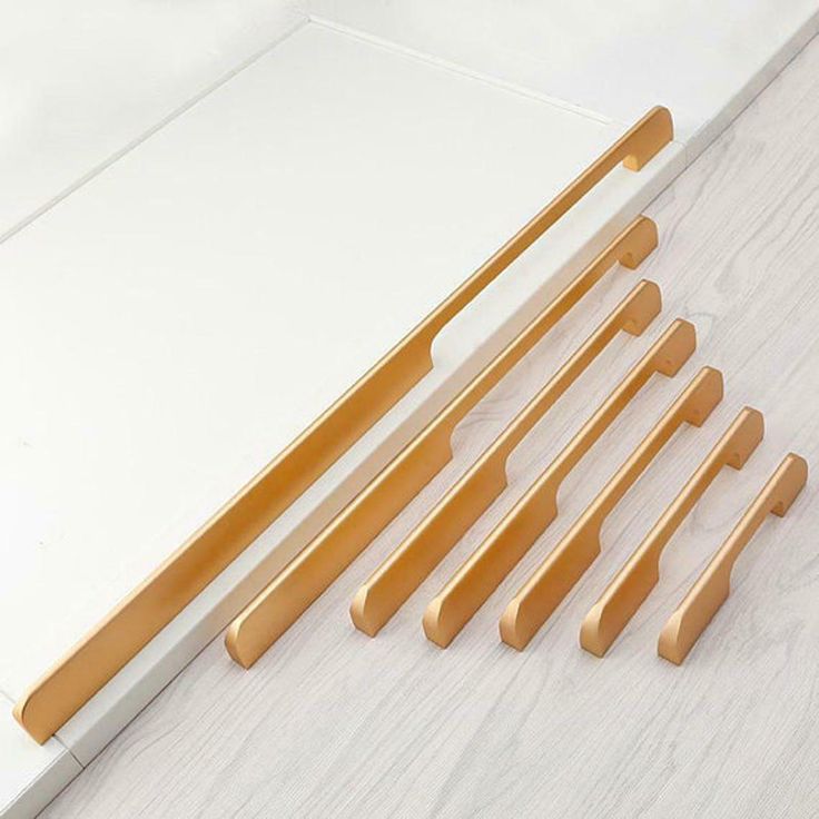 six wooden handles are shown next to a white board on a table with wood trimmings