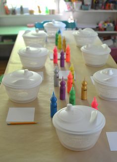 there are many plastic containers on the table with crayons and markers all over them